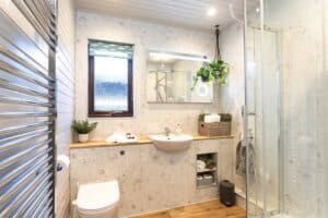 Bright modern bathroom with rain shower at Sandmartin Lodge